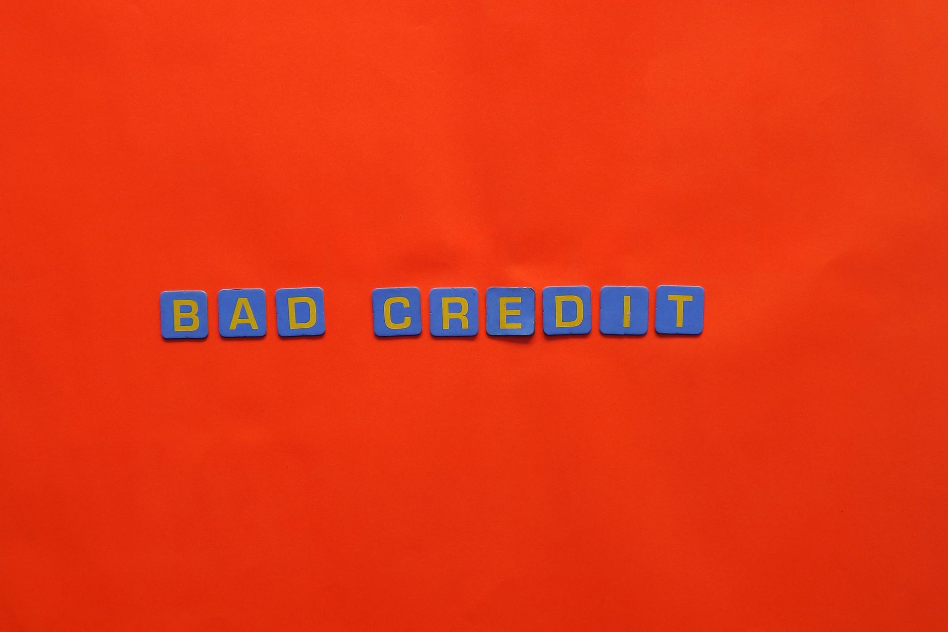 Blue letter blocks spelling 'Bad Credit' on an orange background.