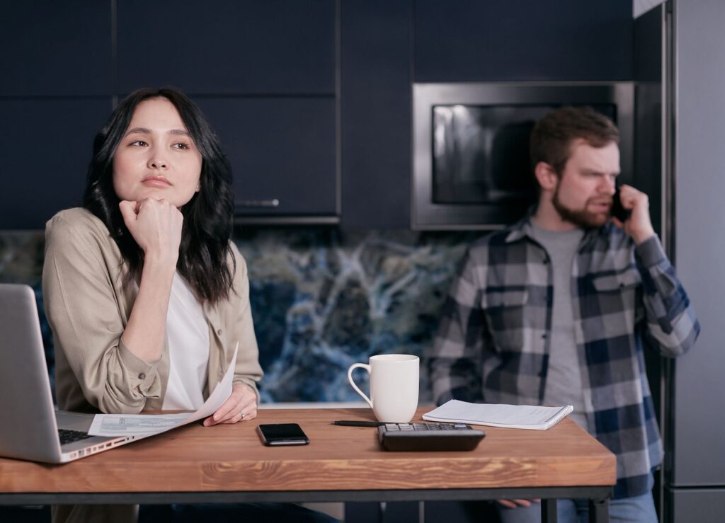 A couple in their kitchen, focused on financial planning and budgeting, showcasing stress and teamwork.